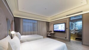 A hotel room with two beds, a desk, a TV, and a bathroom with a mirror and lights. - Mercure Qingdao Downtown (Qingdao)