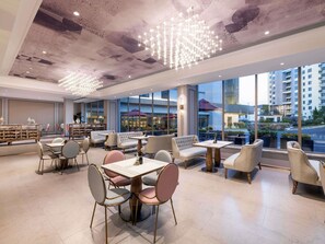 A modern hotel lobby with seating areas, a bar, and large windows offering city views. - Mercure Qingdao Downtown (Qingdao)