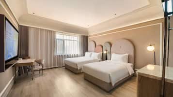 A hotel room with two beds, a desk, a chair, and a television.