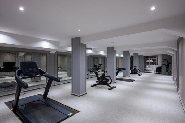 Un gimnasio moderno con cintas de correr, bicicletas estáticas y equipo de ejercicio.