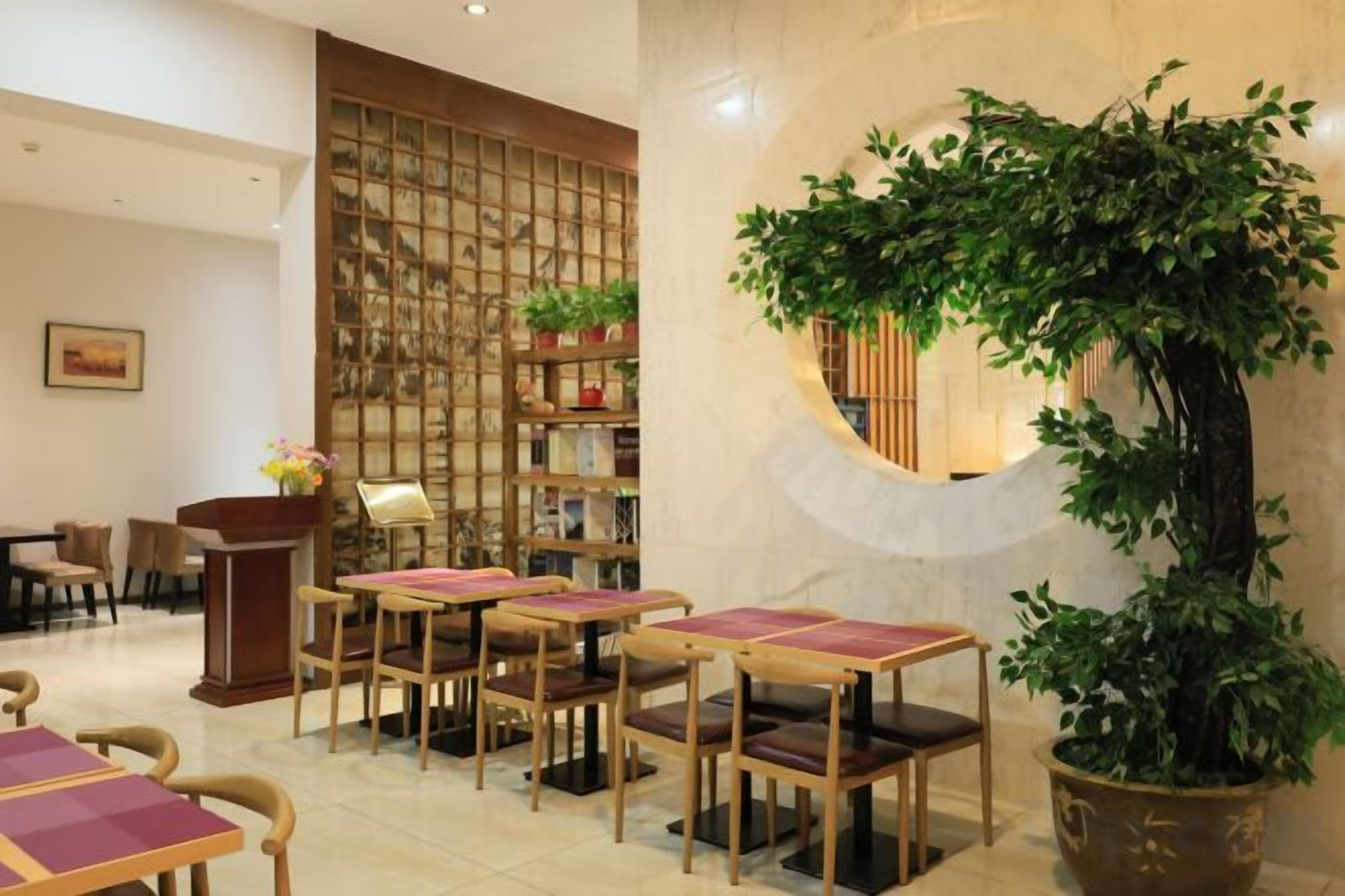 A lobby with a reception desk, seating area, and a large potted plant.
