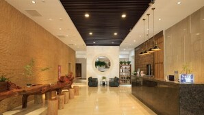 A modern lobby with a wooden reception desk, seating area, and a circular mirror. - Tangyue Hotel (Yan'an)
