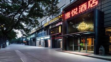 A hotel with a modern facade, a glass entrance, and a visible outdoor seating area.