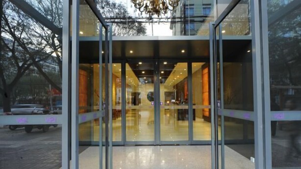 A modern building entrance with glass doors and a reflective floor. - Tangyue Hotel (Yan'an)