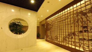 A hallway with a circular window, a tiled floor, and a decorative panel with a grid pattern. - Tangyue Hotel (Yan'an)