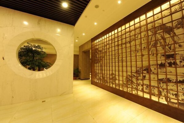 A hallway with a circular window, a tiled floor, and a decorative panel with a grid pattern. - Tangyue Hotel (Yan'an)