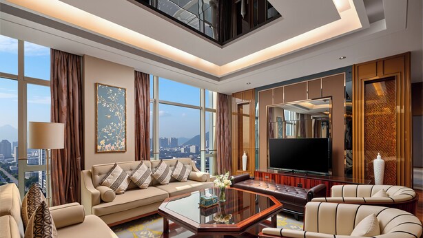 A modern living room with a sofa, armchairs, a coffee table, and a TV.