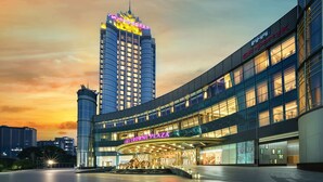 A modern hotel with a prominent entrance and a high-rise building in the background.