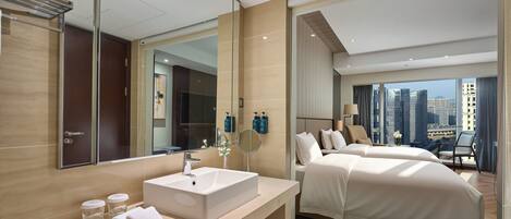 A modern hotel room with a large mirror, a white sink, two beds, a city view, and a balcony.