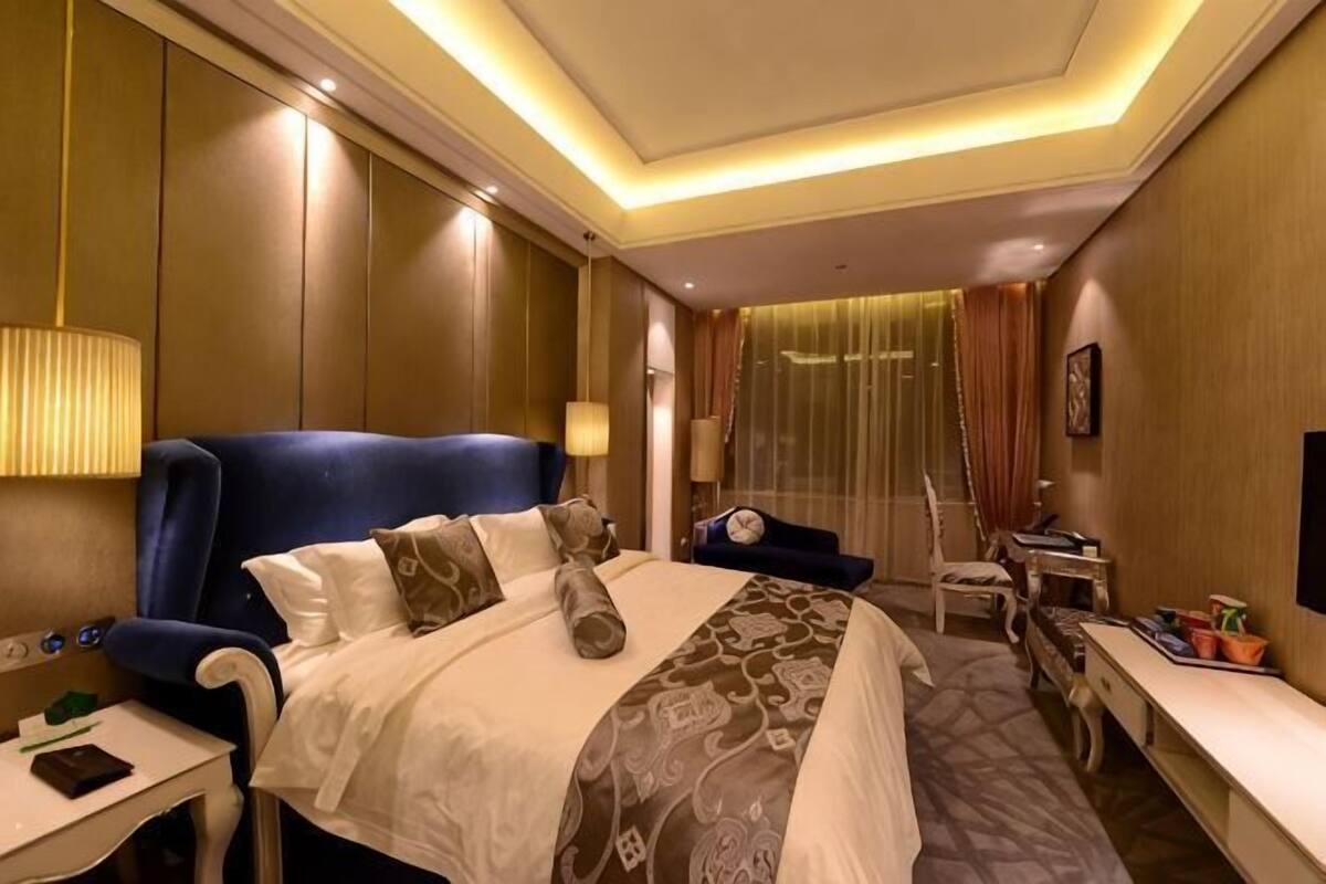 Ein Hotelzimmer mit einem großen Bett, Nachttischen, einem Schreibtisch und einem Sessel.