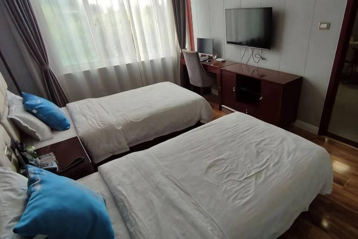 A hotel room with two beds, a desk, a TV, and a wardrobe.