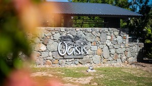 A stone wall with a metal sign reading "Oasis on Hamilton Two." - Oasis 26 (Whitsundays)
