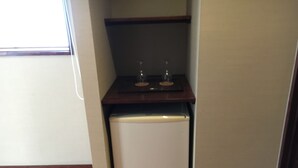 Une cuisine de taille réduite, avec un réfrigérateur blanc, un plan de travail en bois et un petit évier.