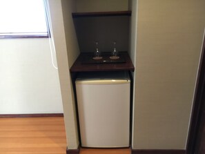 Une cuisine de taille réduite, avec un réfrigérateur blanc, un plan de travail en bois et un petit évier.