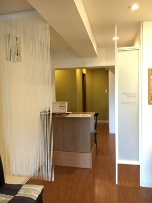 A reception area with a wooden desk, a hanging decorative piece, and a sign indicating a massage salon. - Otaru Furukawa Hotel (Otaru)