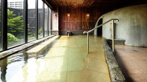 Une piscine dotée d’un plafond en bois, d’un mur en pierre et d’une rambarde en métal.