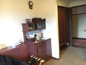 Une chambre d’hôtel équipée d’un bureau, d’un téléphone, d’une horloge, d’un petit coin salon et d’une porte donnant sur une autre chambre.