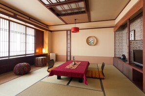A traditional Japanese room with tatami flooring, a low table with a red tablecloth, a television, and a sliding door. - Otaru Furukawa Hotel (Otaru)