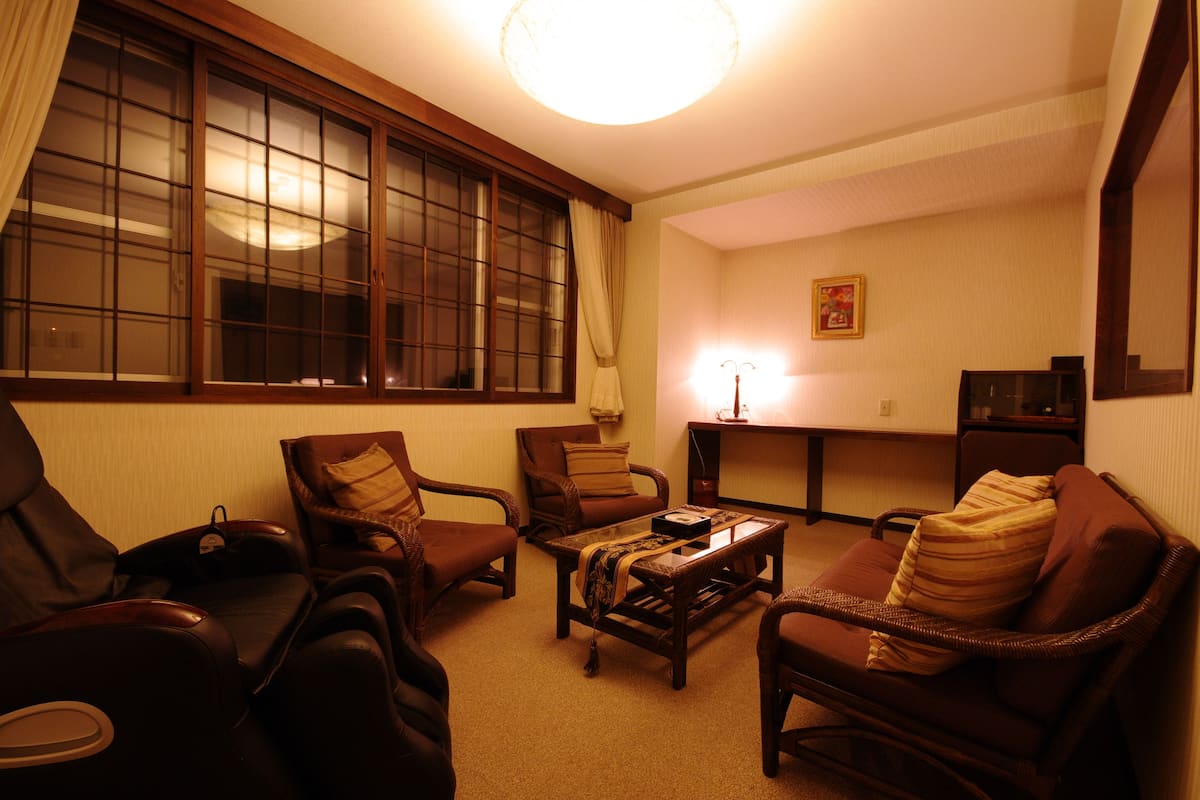 A living room with a massage chair, a sofa, a coffee table, and a TV stand.