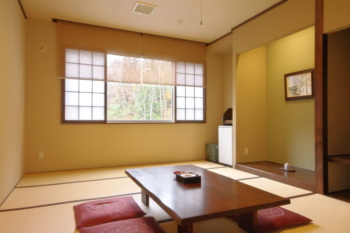 A traditional Japanese room with tatami flooring, a low wooden table, and a sliding door.