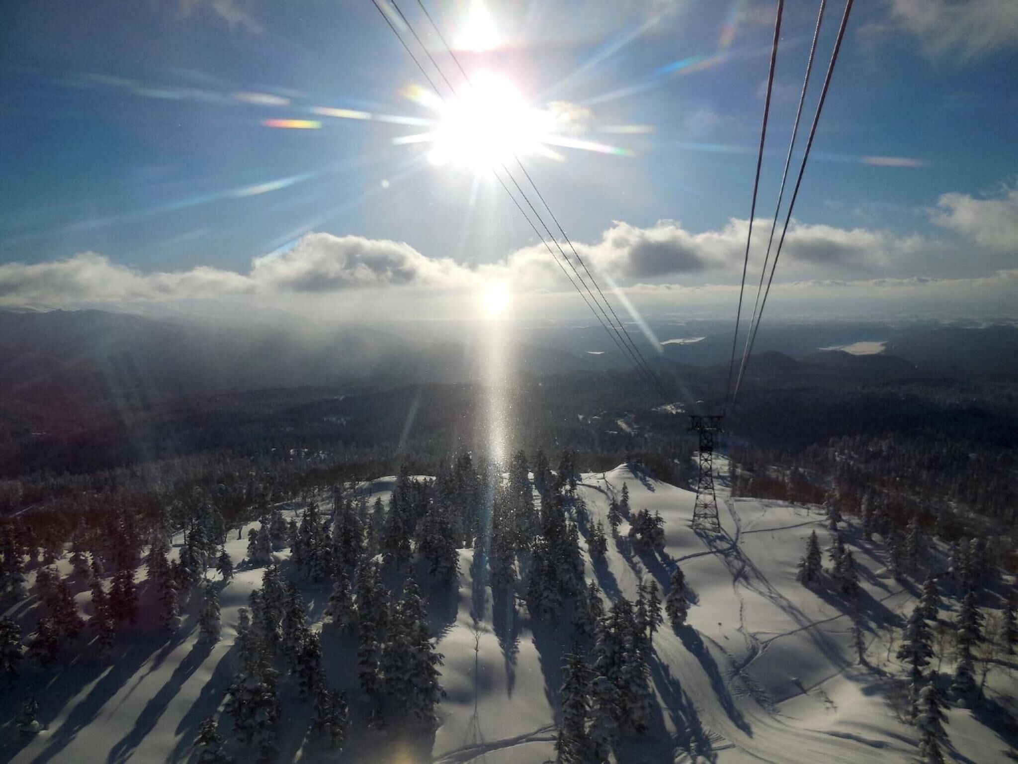 A snowy mountain landscape with a ski lift and a clear sky.