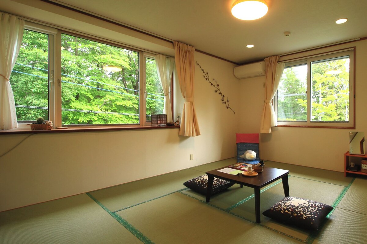 A traditional Japanese room with tatami flooring, a low table, and a futon bed.