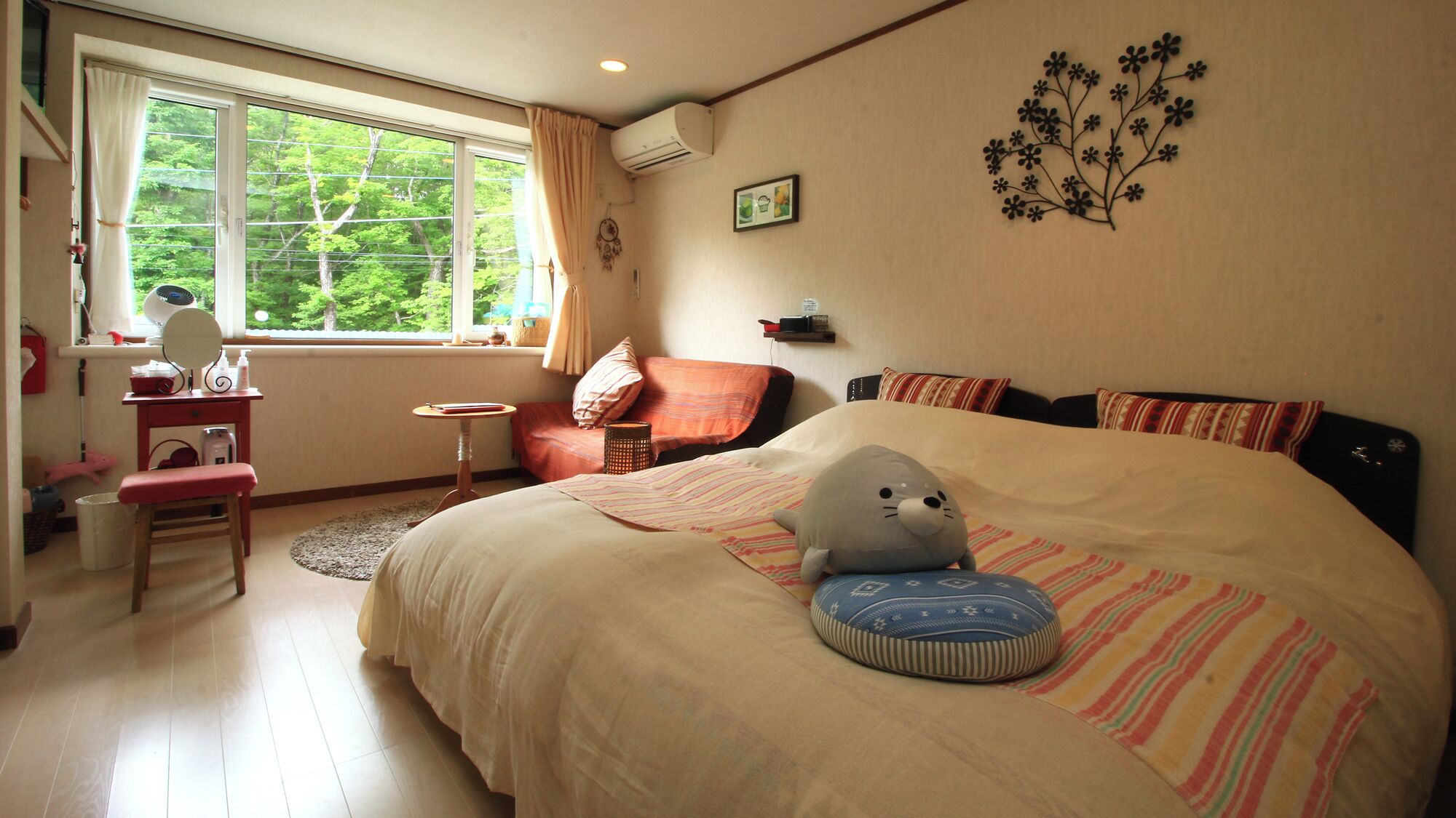 A bedroom with a bed, a desk, a chair, and a window with a view of trees.