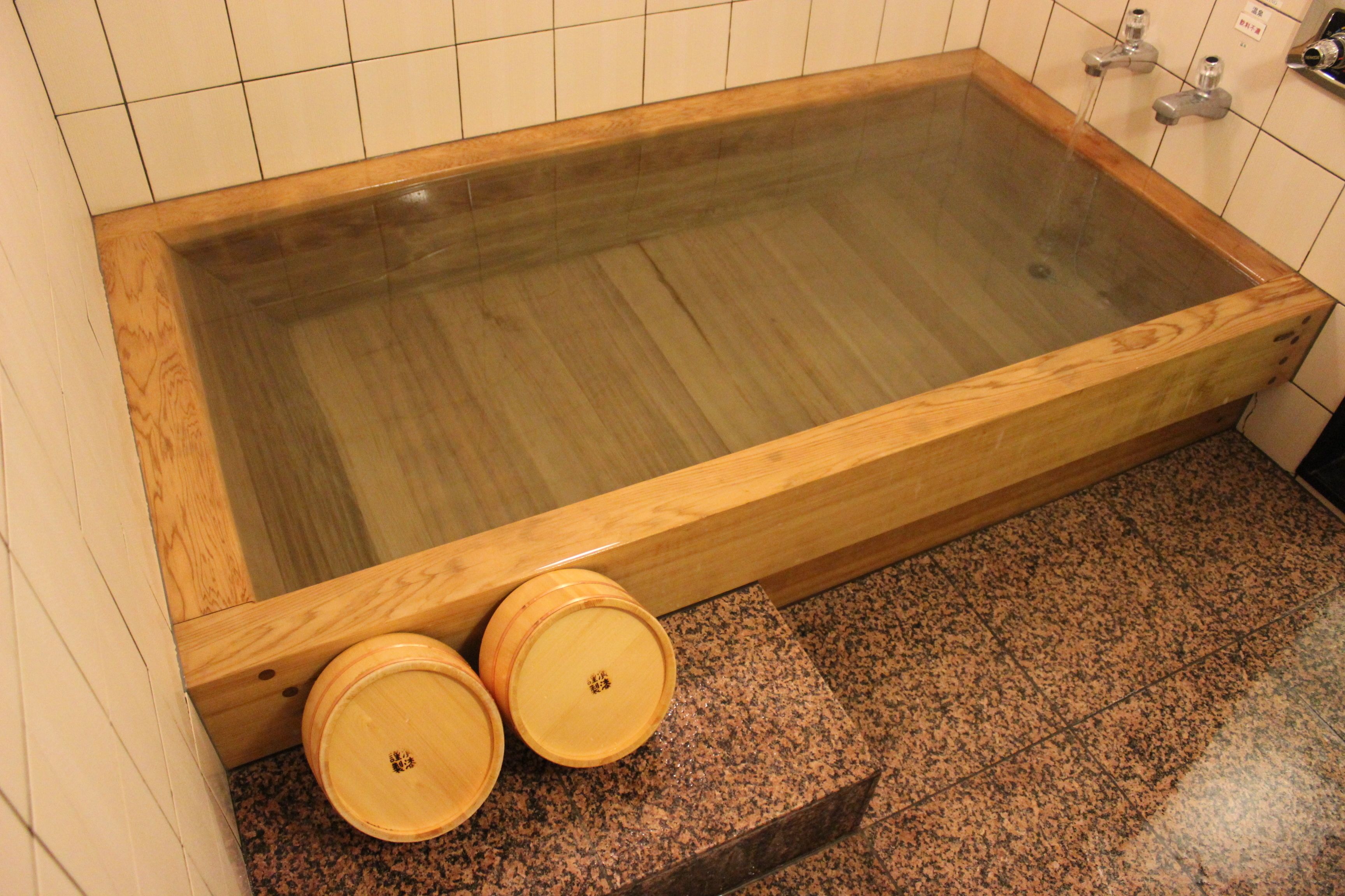 A wooden bathtub with two wooden buckets at the bottom.