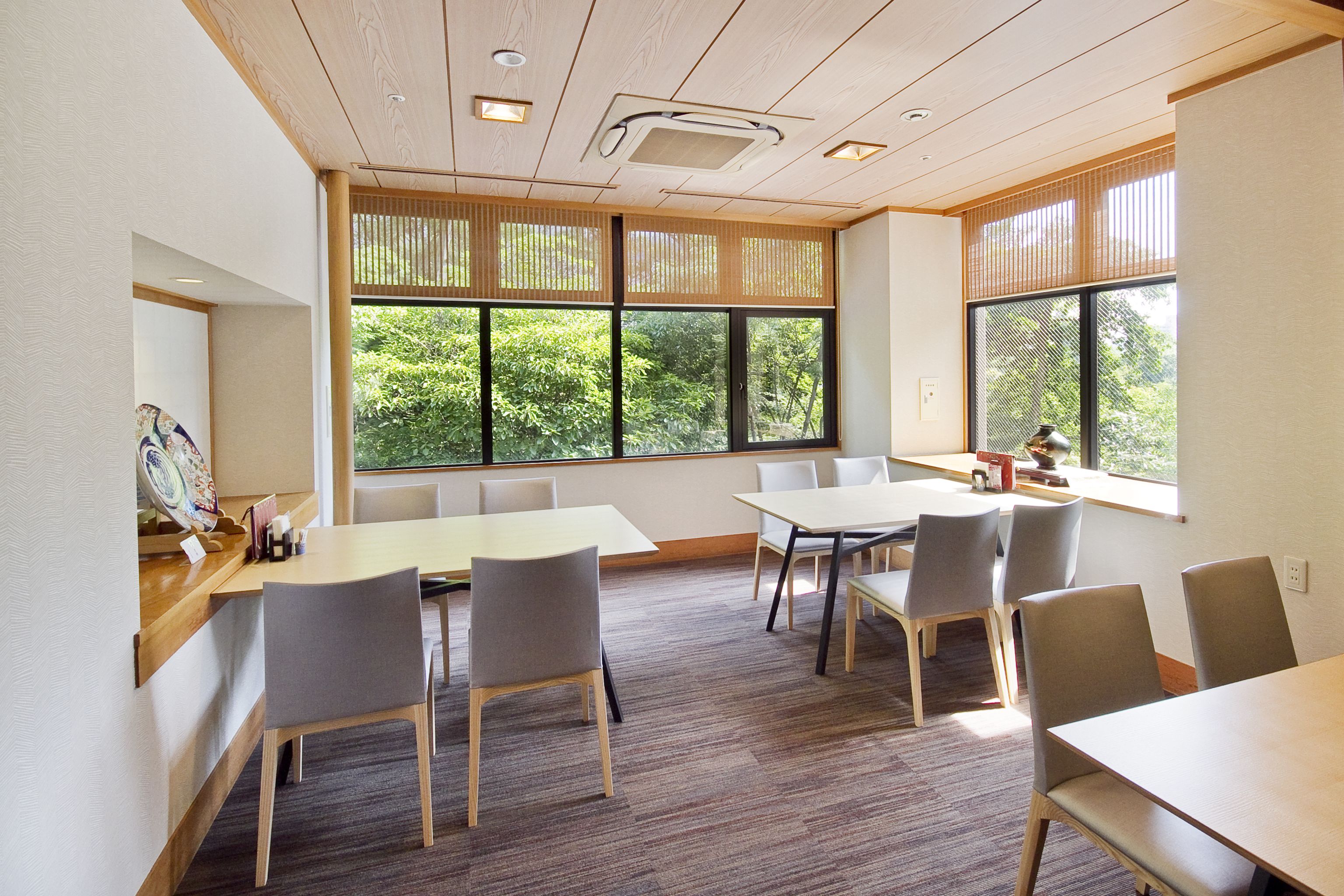 A conference room with large windows, wooden ceiling, and modern furniture.
