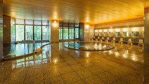 A spacious indoor swimming pool with a wooden ceiling, stone walls, and a seating area with benches. - Dogo Onsen Funaya (Matsuyama)
