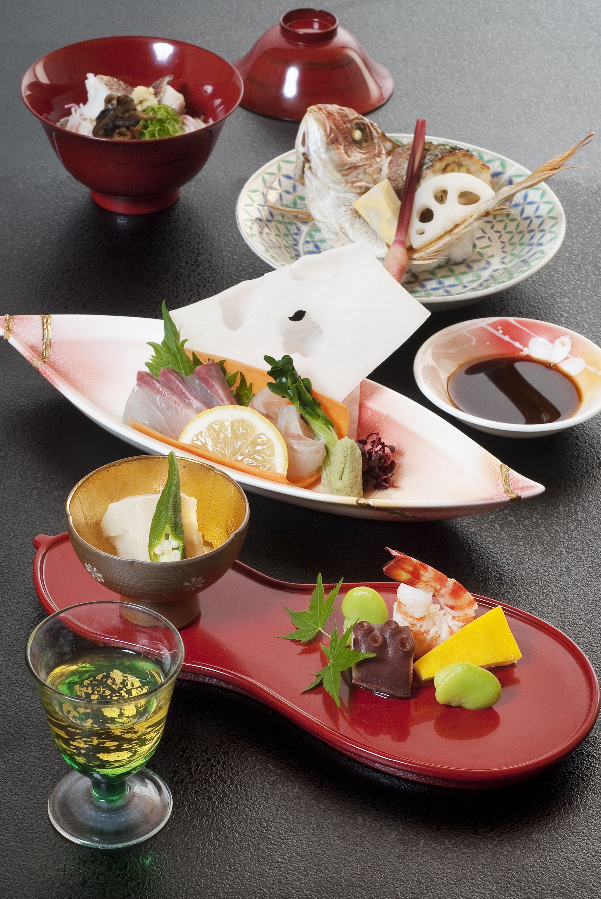 A variety of Japanese dishes including sashimi, sushi, and a glass of sake.
