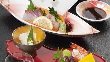 A variety of Japanese dishes including sashimi, sushi, and a glass of sake.