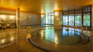 A large indoor swimming pool with a wooden ceiling, stone walls, and a bench by the pool. - Dogo Onsen Funaya (Matsuyama)