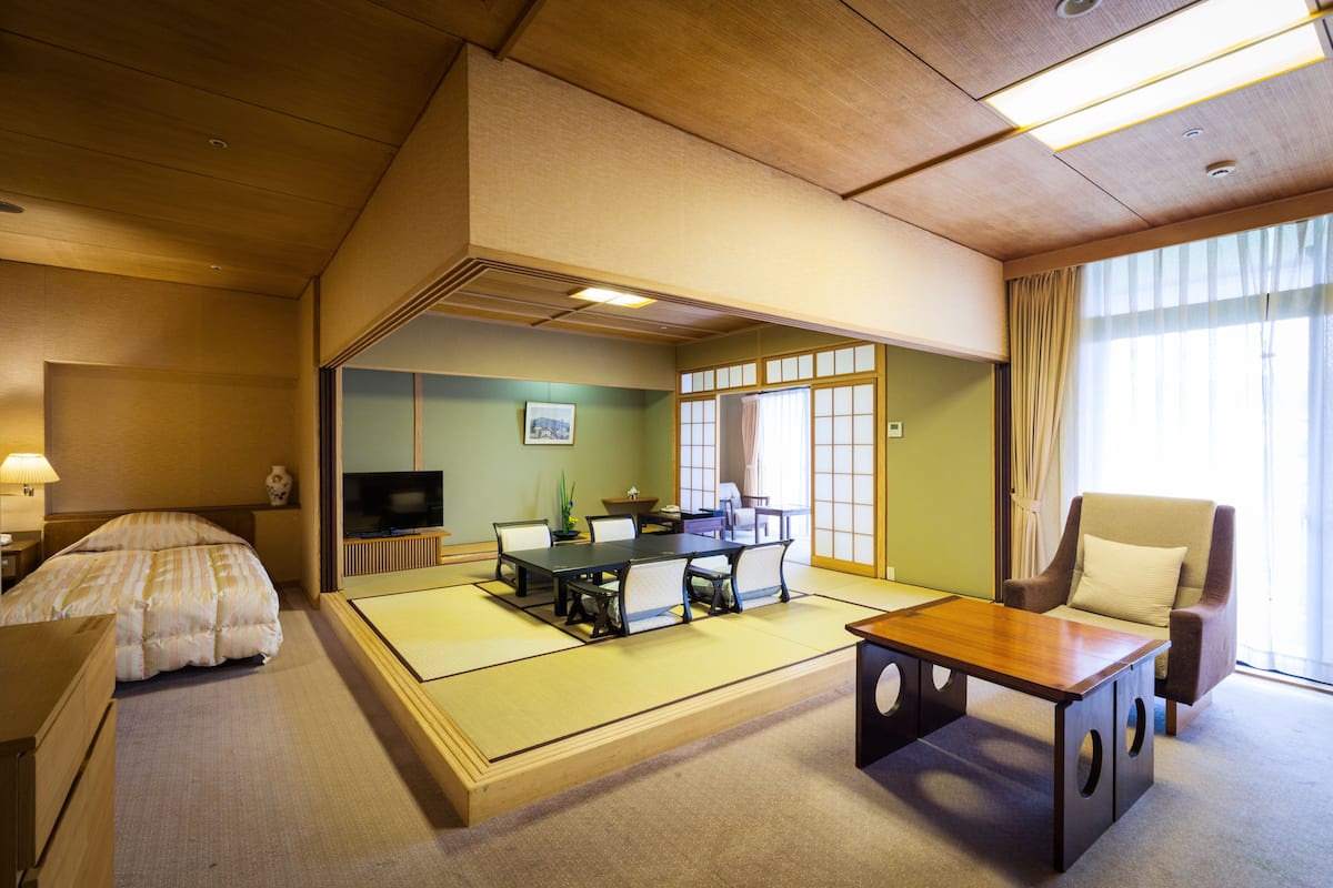 Een traditionele Japanse kamer met tatami vloeren, een lage tafel, een bank en een televisie.