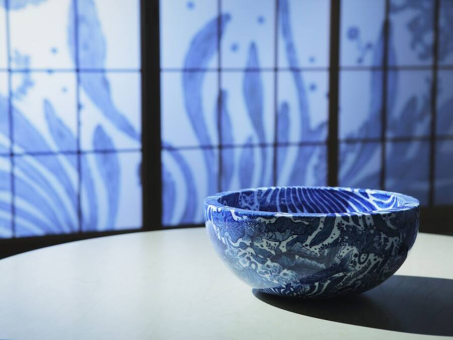 A blue ceramic bowl on a table with a tiled wall in the background.