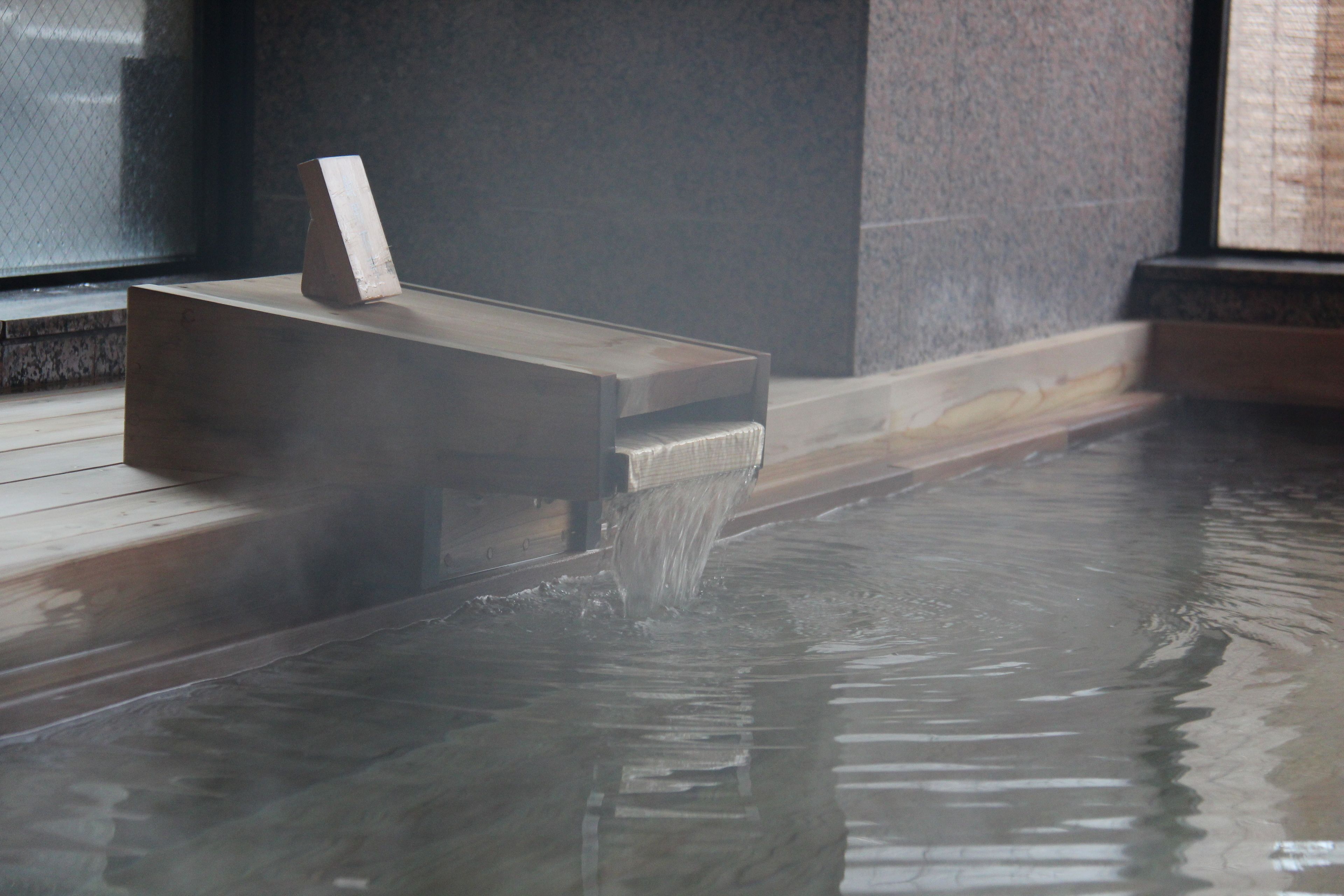A hot tub with a wooden platform and a waterfall feature.