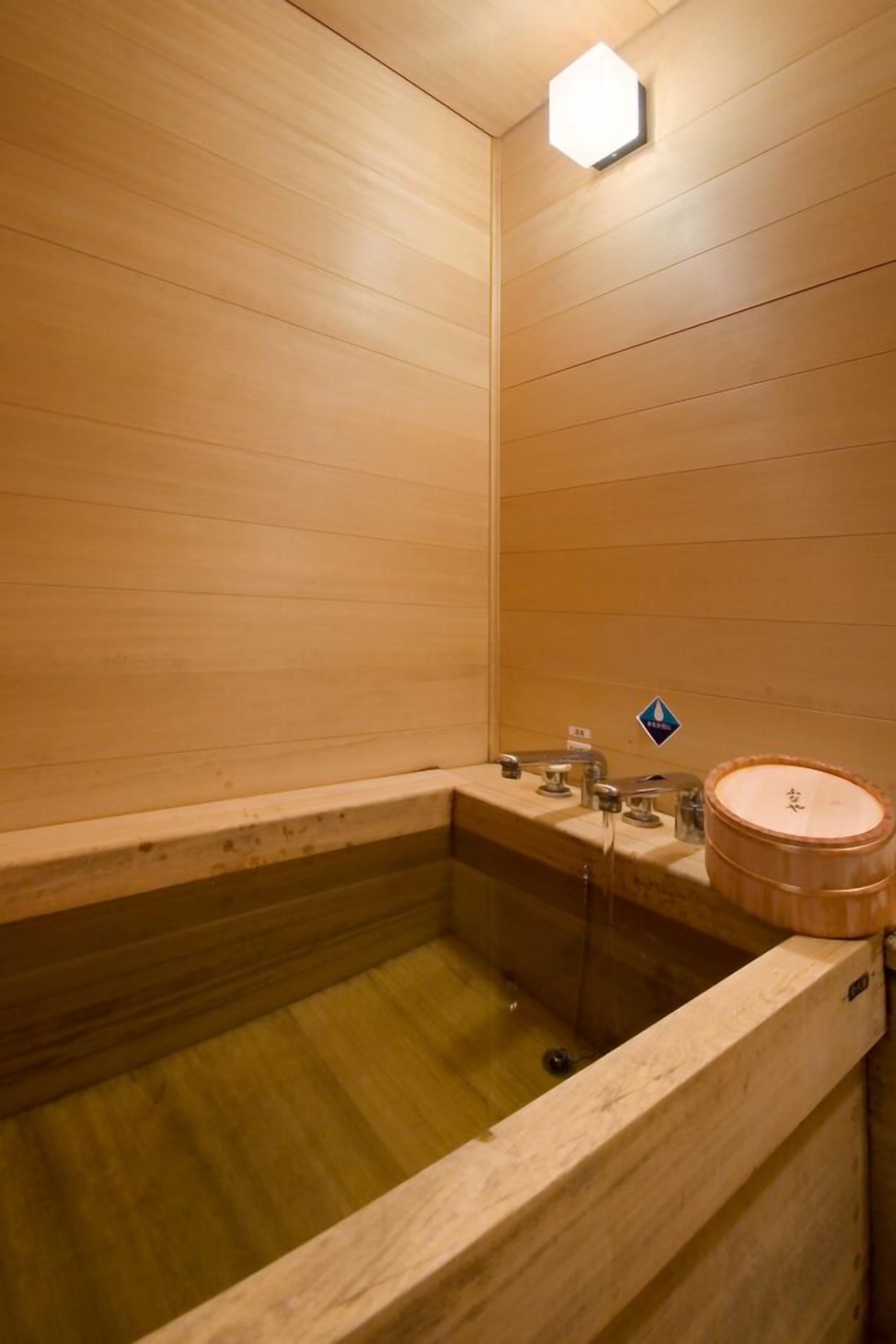 A wooden interior with a bathtub, a sink, and a wooden barrel.
