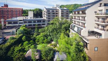 A multi-story hotel with balconies, a rooftop garden, and a traditional thatched-roof structure.