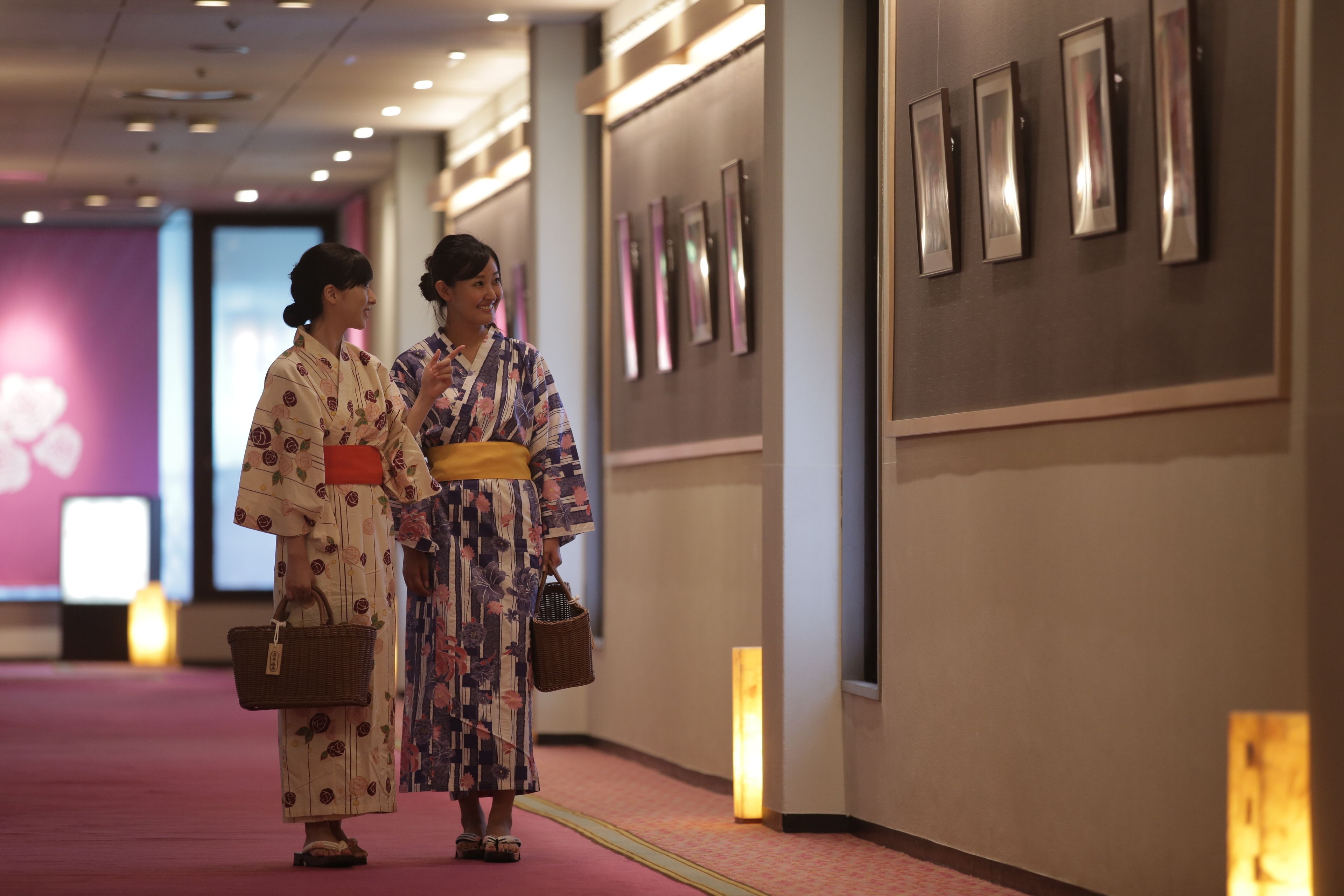 A hallway with framed pictures on the wall and a red carpet.