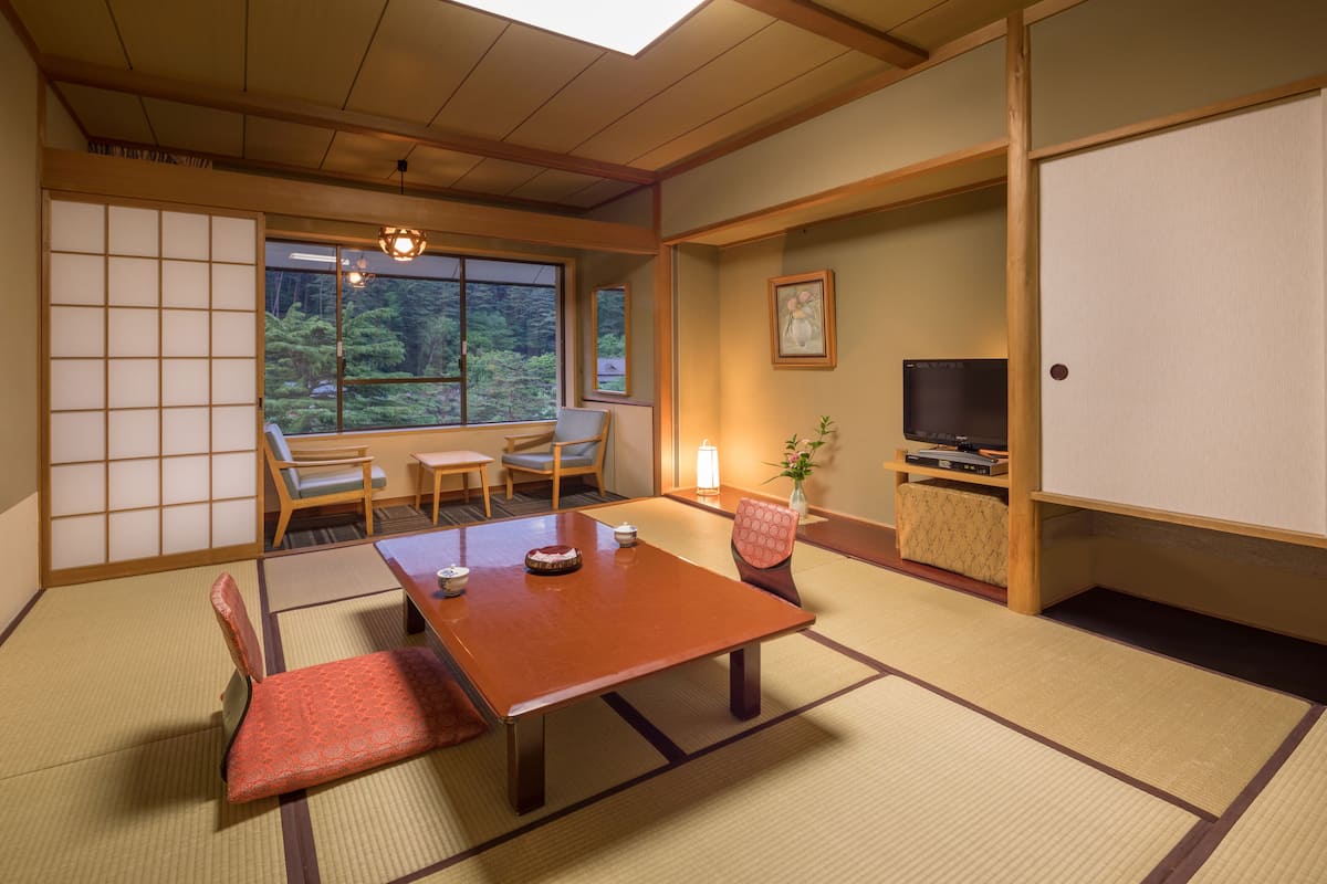 Ett traditionellt japanskt rum med tatamimattor på golvet, ett lågt bord och en tv som står på en hylla.