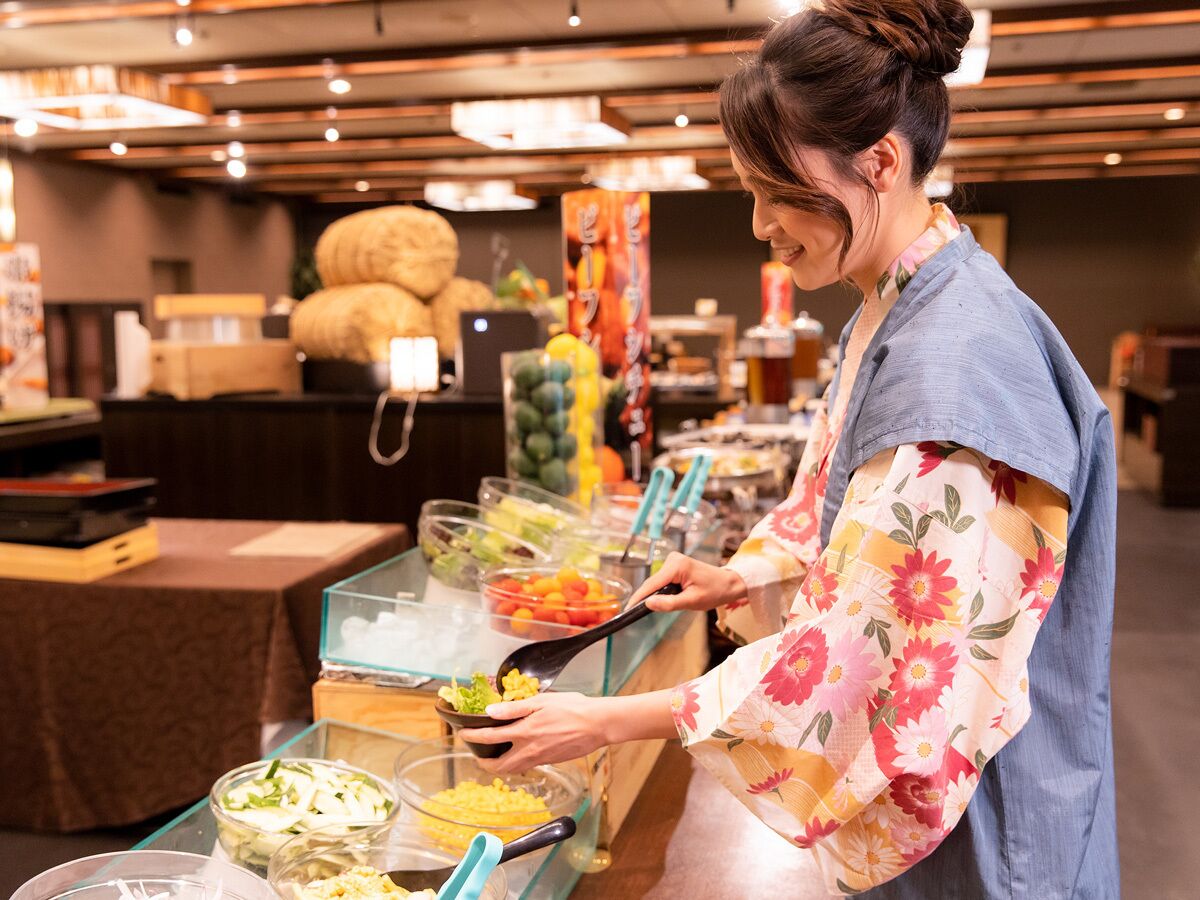 Una barra de buffet con diferentes opciones de comida y una persona sirviéndose.