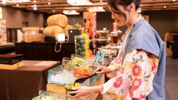 Una barra de buffet con diferentes opciones de comida y una persona sirviéndose.