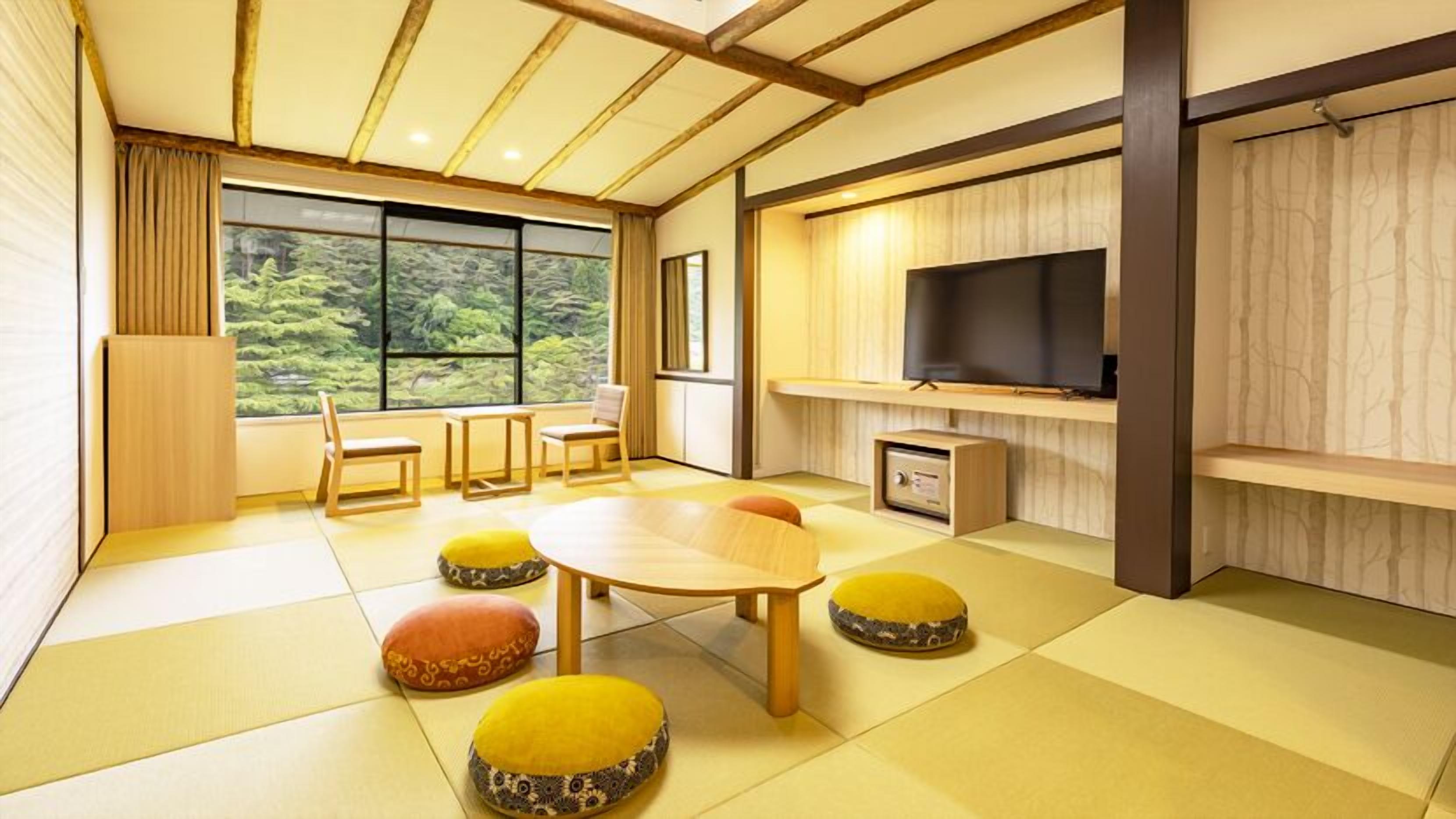 A modern living room with a large window, a wooden dining table, and a television.