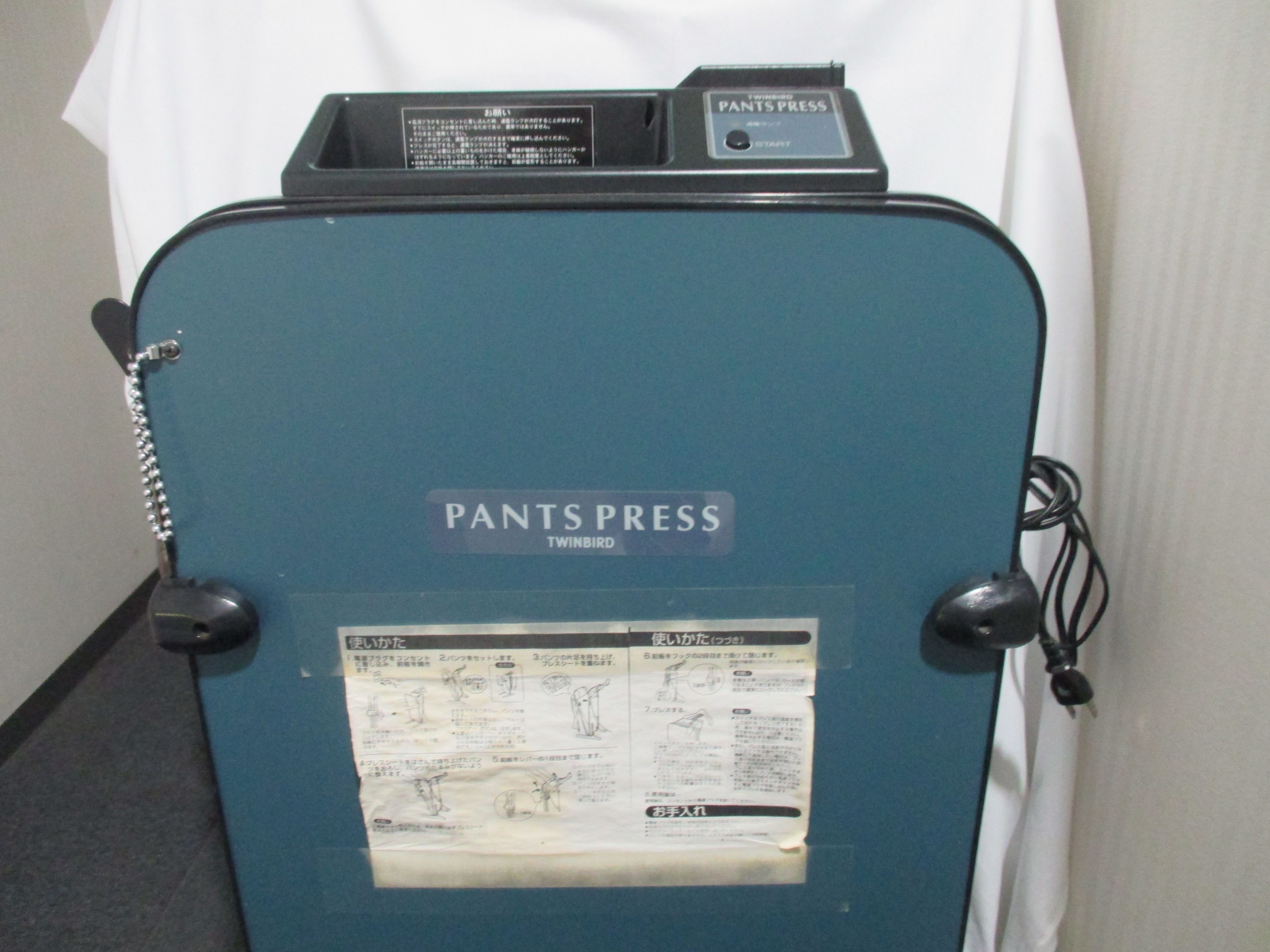 Una máquina para planchar pantalones azul, con una etiqueta que dice 'PANTS PRESS' y 'TWINBIRD'.