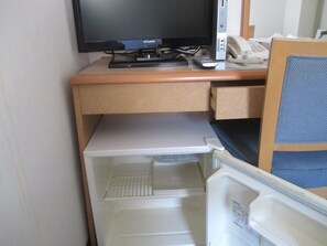 A compact room with a desk, a television, a telephone, and a refrigerator. - Hotel Green Well (Sendai)