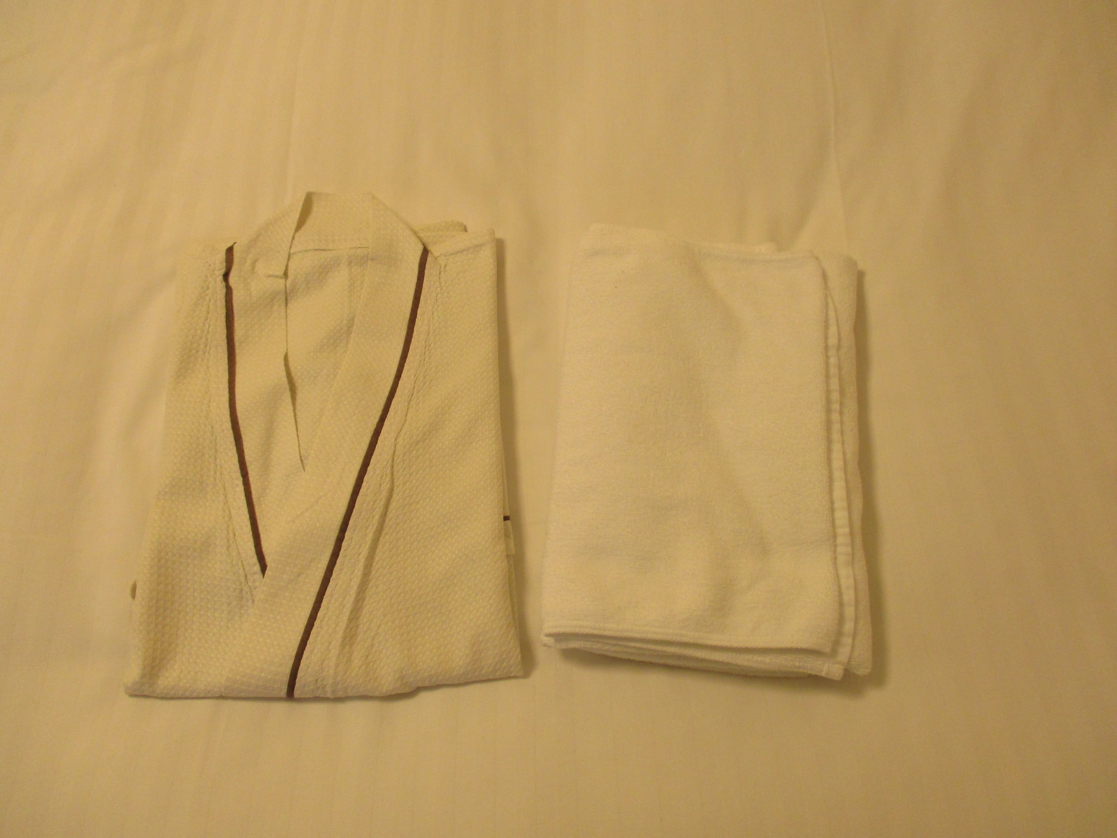 Duas camisas brancas dobradas sobre um fundo neutro.