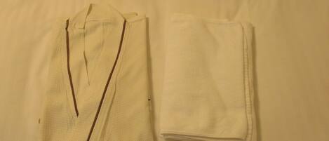 Duas camisas brancas dobradas sobre um fundo neutro.
