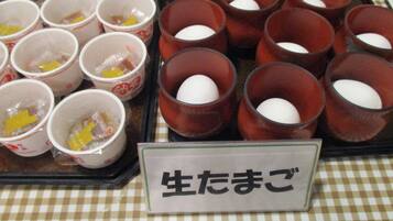 Uma bandeja com diversos copos contendo alimentos, alguns com gemas de ovo visíveis, e uma placa com texto em japonês.