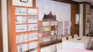 A conference room with tables and chairs, a large bookshelf filled with books, and a clock on the wall. - Fukui Palace INN (Fukui)