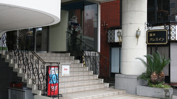A hotel entrance with a staircase, a sign with Japanese characters, and a potted plant. - Fukui Palace INN (Fukui)